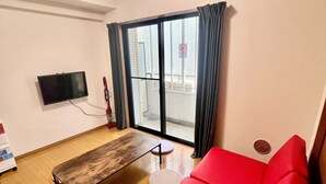 Un soggiorno moderno con un divano rosso, un tavolo di legno e una TV a parete.
