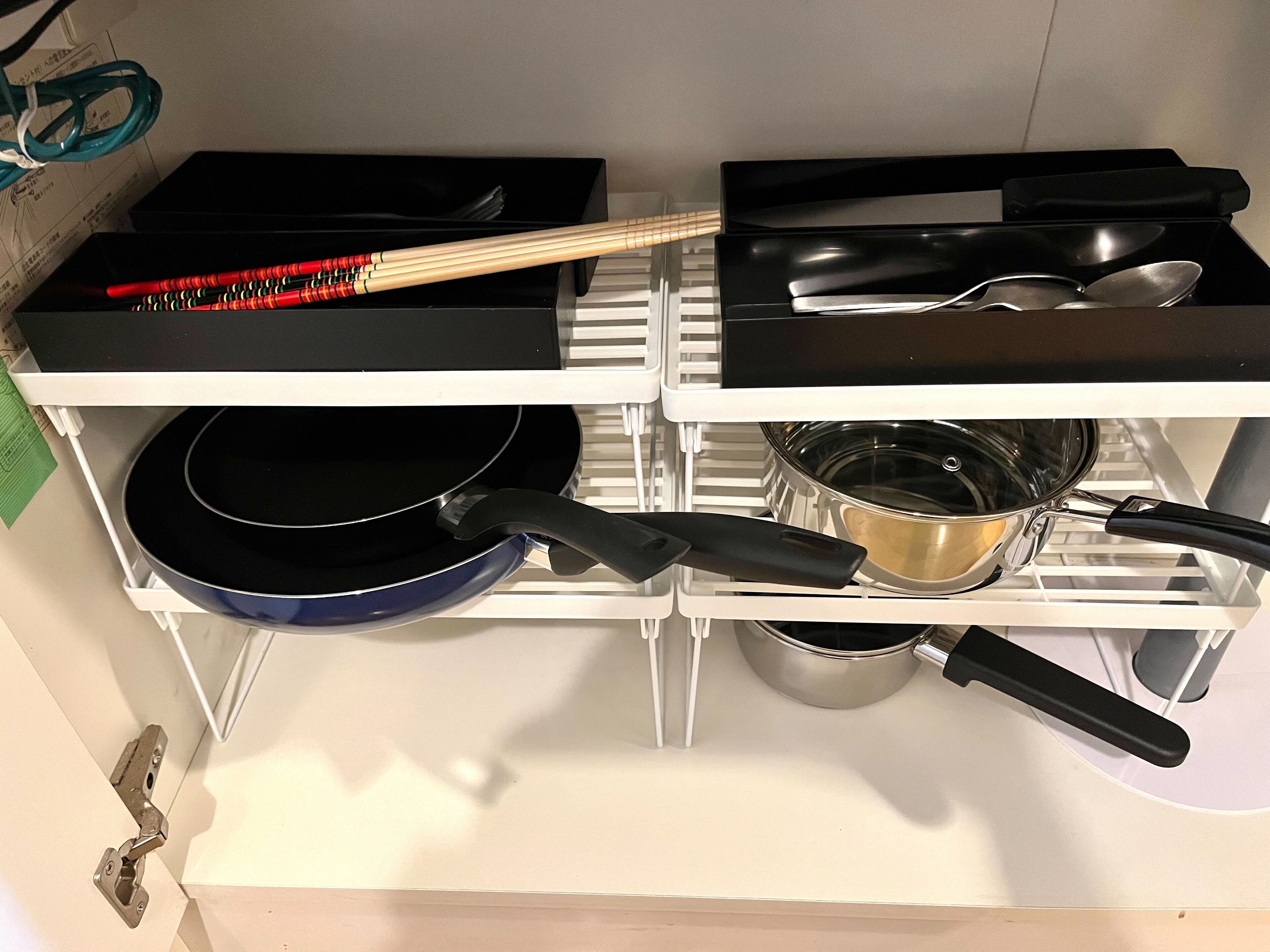 A kitchen with a stove, pots, pans, and a set of chopsticks.