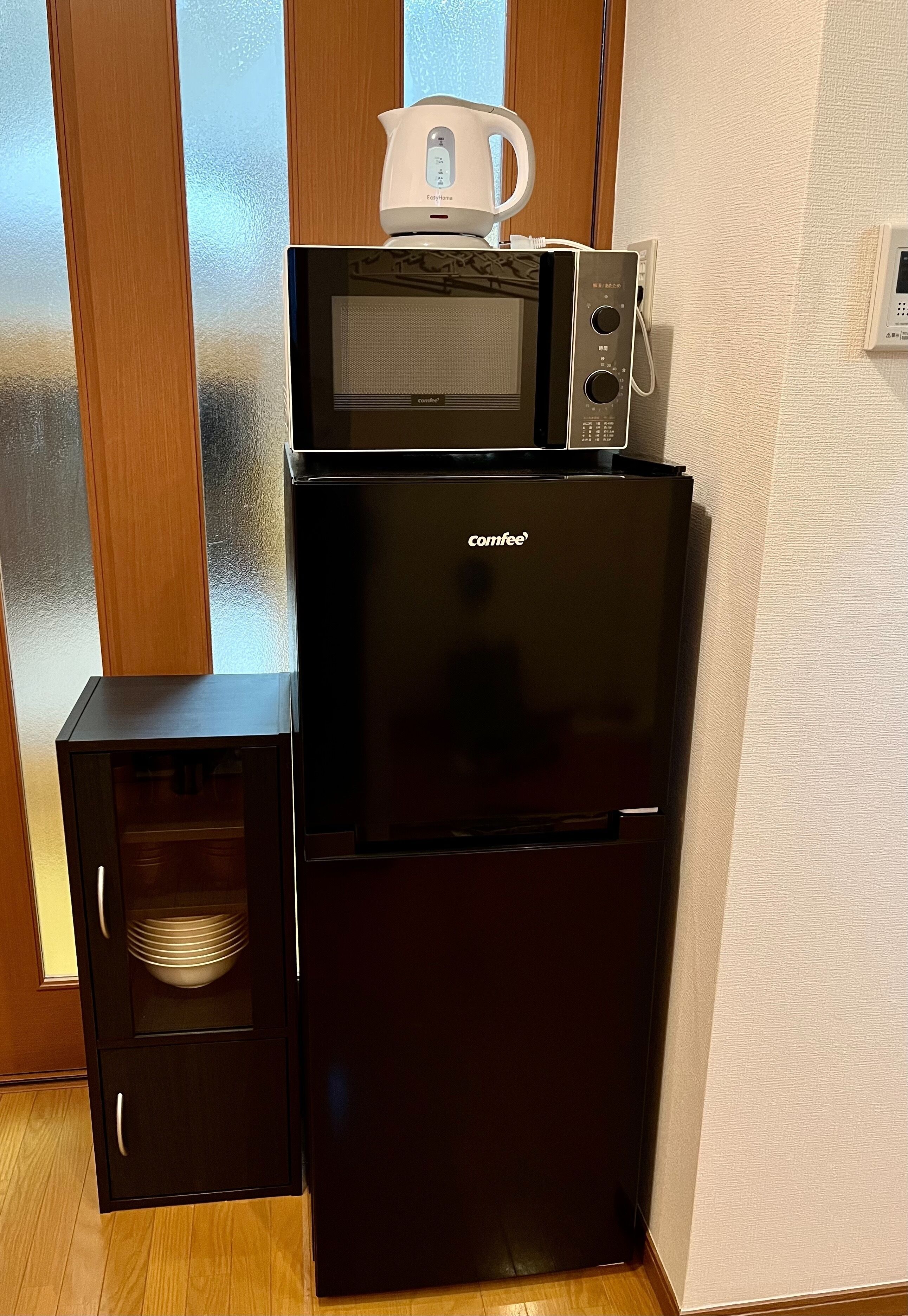 A compact kitchen with a black refrigerator, a microwave, and a small oven.