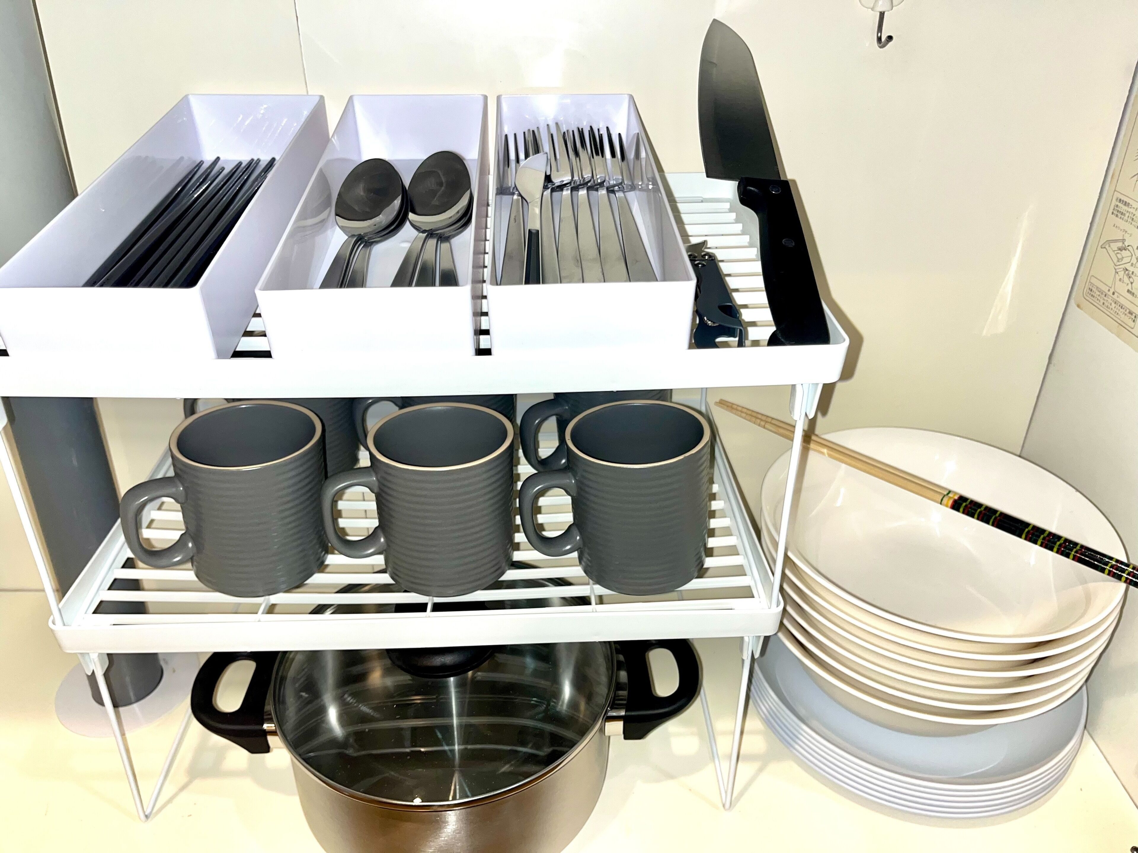 A kitchen area with a utensil organizer, a pot, and stacked plates.