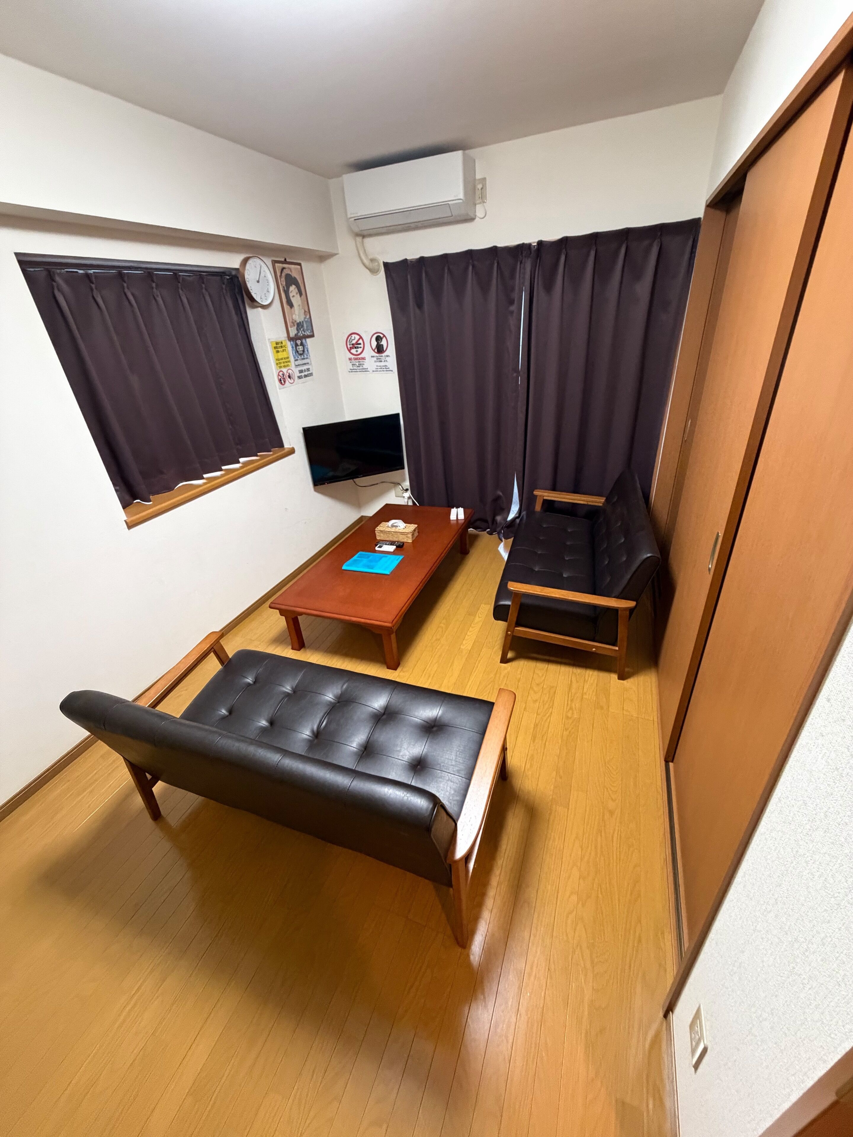 A compact room with a bed, a small table, a TV, and a window with curtains.
