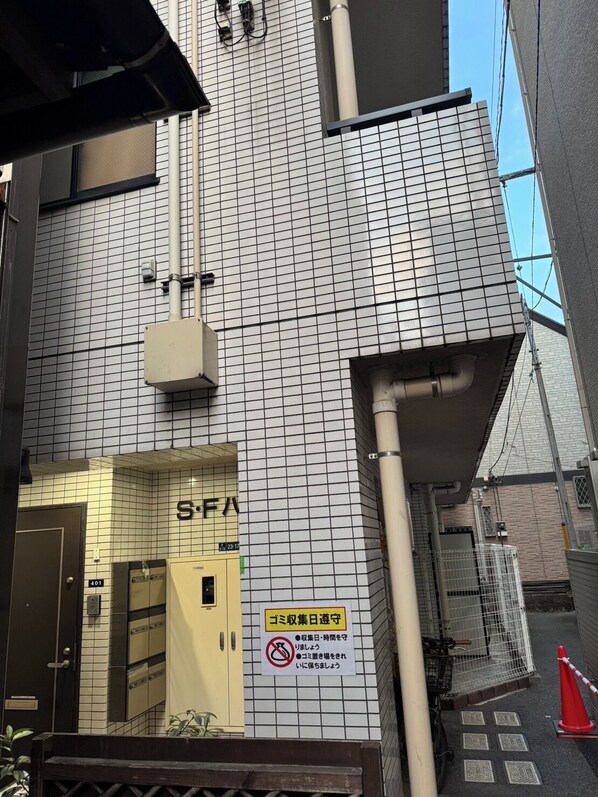 Un edificio con fachada de azulejos, un ascensor visible y un letrero con texto en japonés.