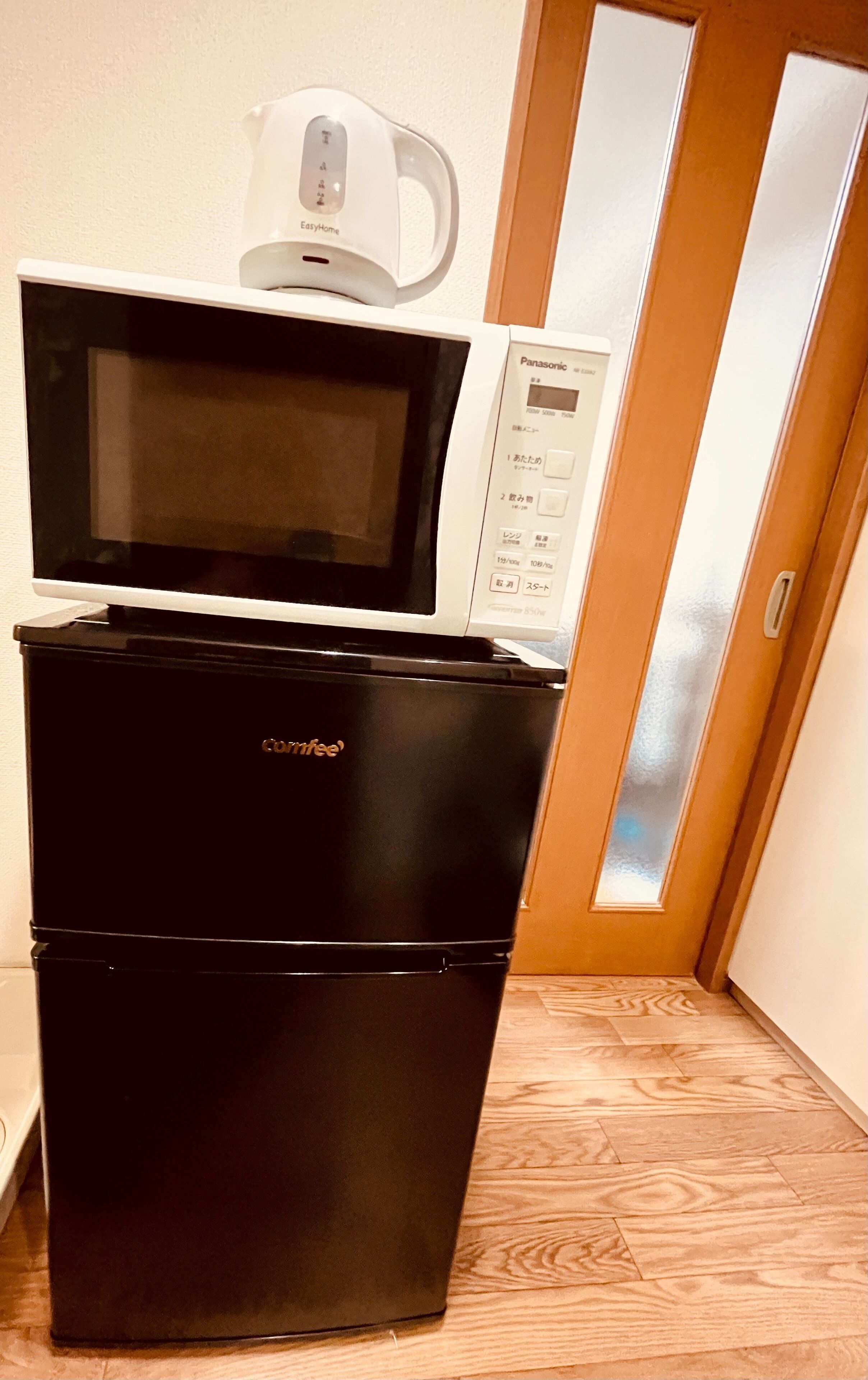 A compact kitchen with a black refrigerator, a microwave, and a coffee maker on top.