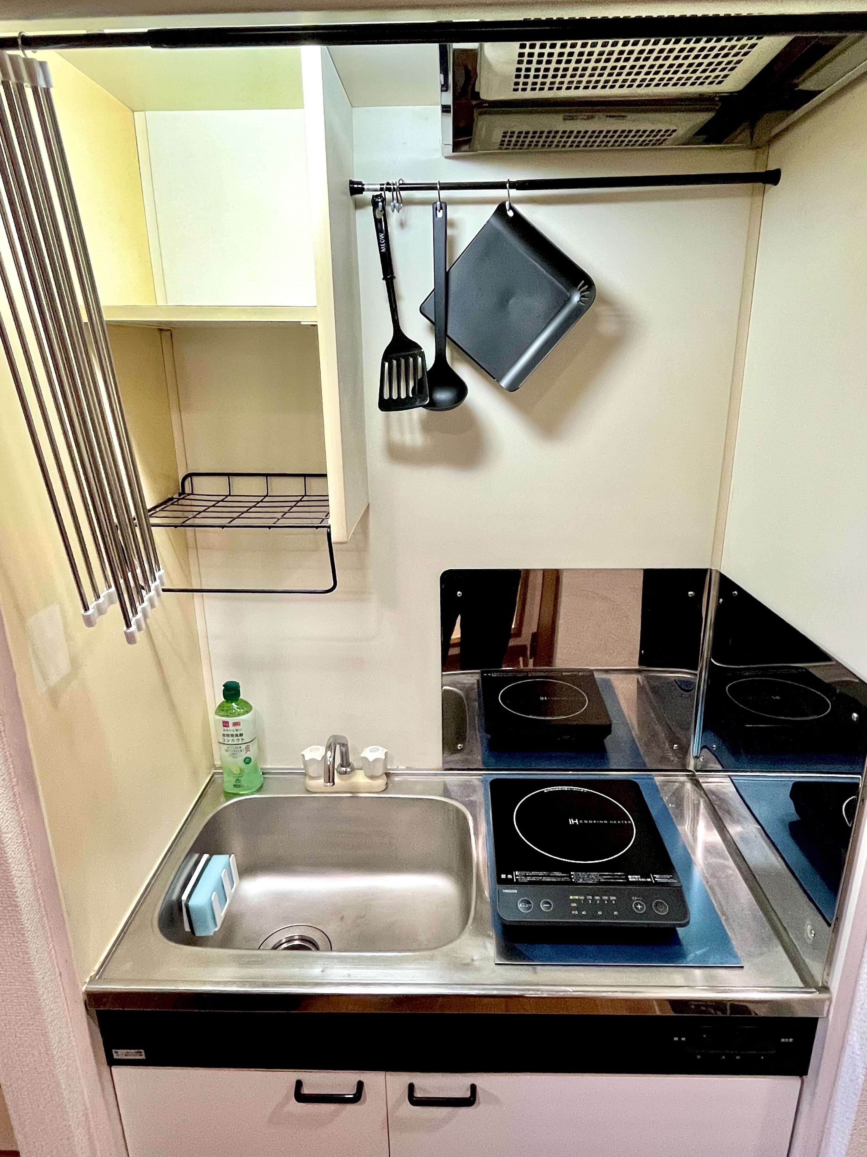 A compact kitchen with a stainless steel sink, a built-in stove, and a drying rack.