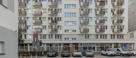 A multi-story residential building with balconies, a parking lot, and a store named "XERO".