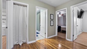 A hallway with wooden flooring, white doors, and a ceiling fan.