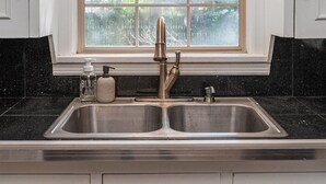 A kitchen with a double sink, a window above the sink, and white cabinets.