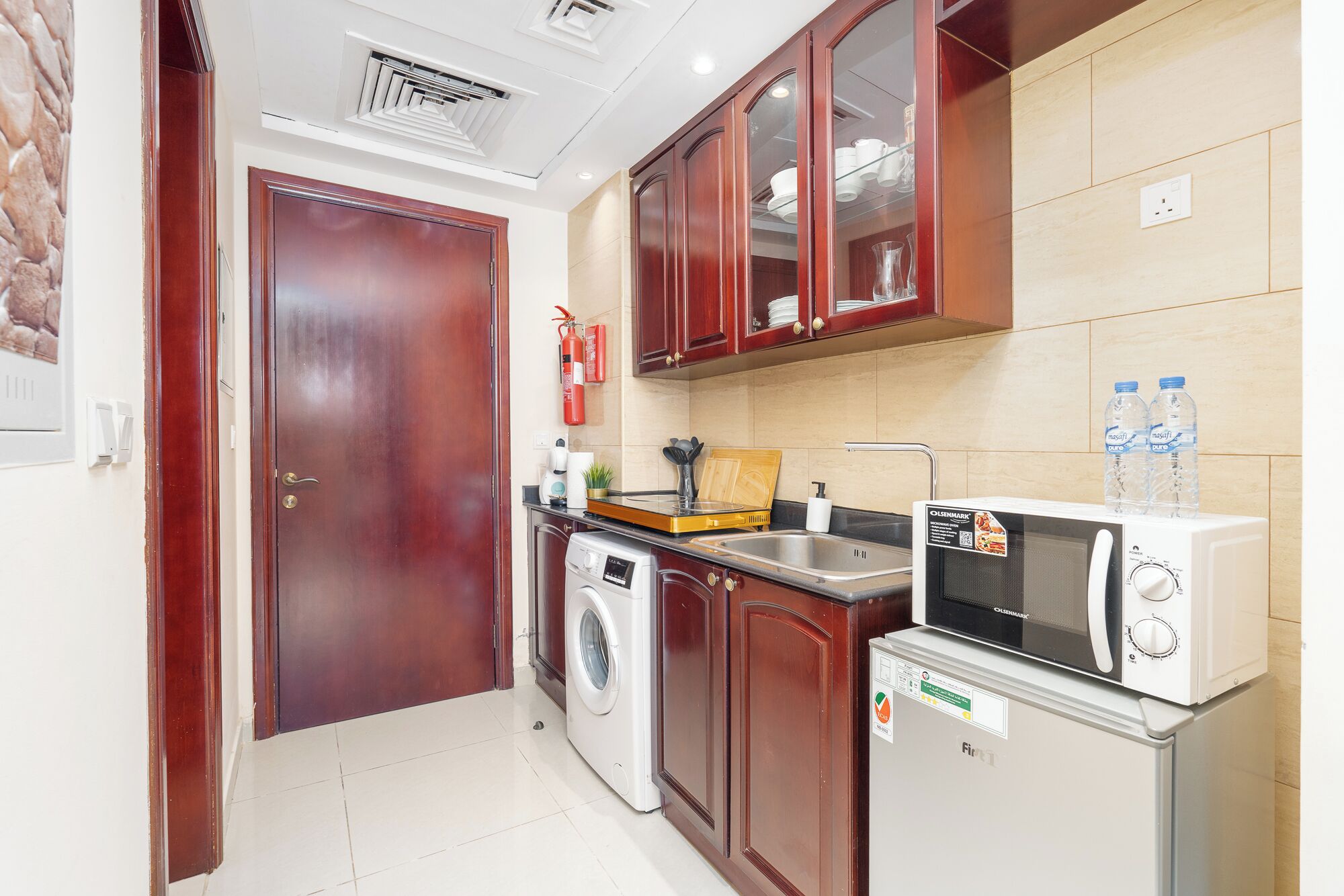 A compact kitchen with a washing machine, a microwave, and a sink.