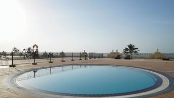 Relax by the pool surrounded by palm trees and a clear sky.