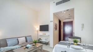 Un salon moderne avec un canapé, une table basse et un téléviseur. Il y a également un coin repas avec une table dressée pour deux personnes.