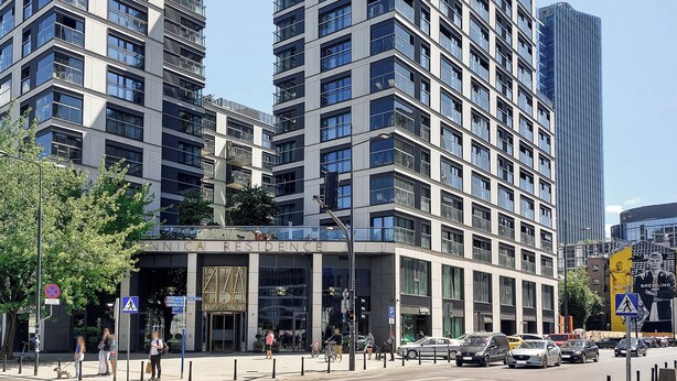 Un edificio moderno de rascacielos con varios pisos, ventanas amplias y una entrada destacada.