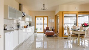 Cocina moderna con armarios blancos, una isla central y un comedor con mesa y sillas.