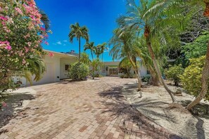 A paved courtyard with palm trees and a building in the background.