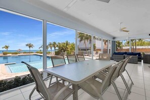 A dining area with a view of a pool and palm trees.