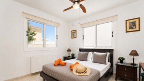 Una camera da letto con un letto, due comodini, una ventola a soffitto e una finestra vista.