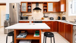 Una cucina moderna con mobili in legno, un frigorifero in acciaio inox, un forno a microonde e una macchina da caffè.