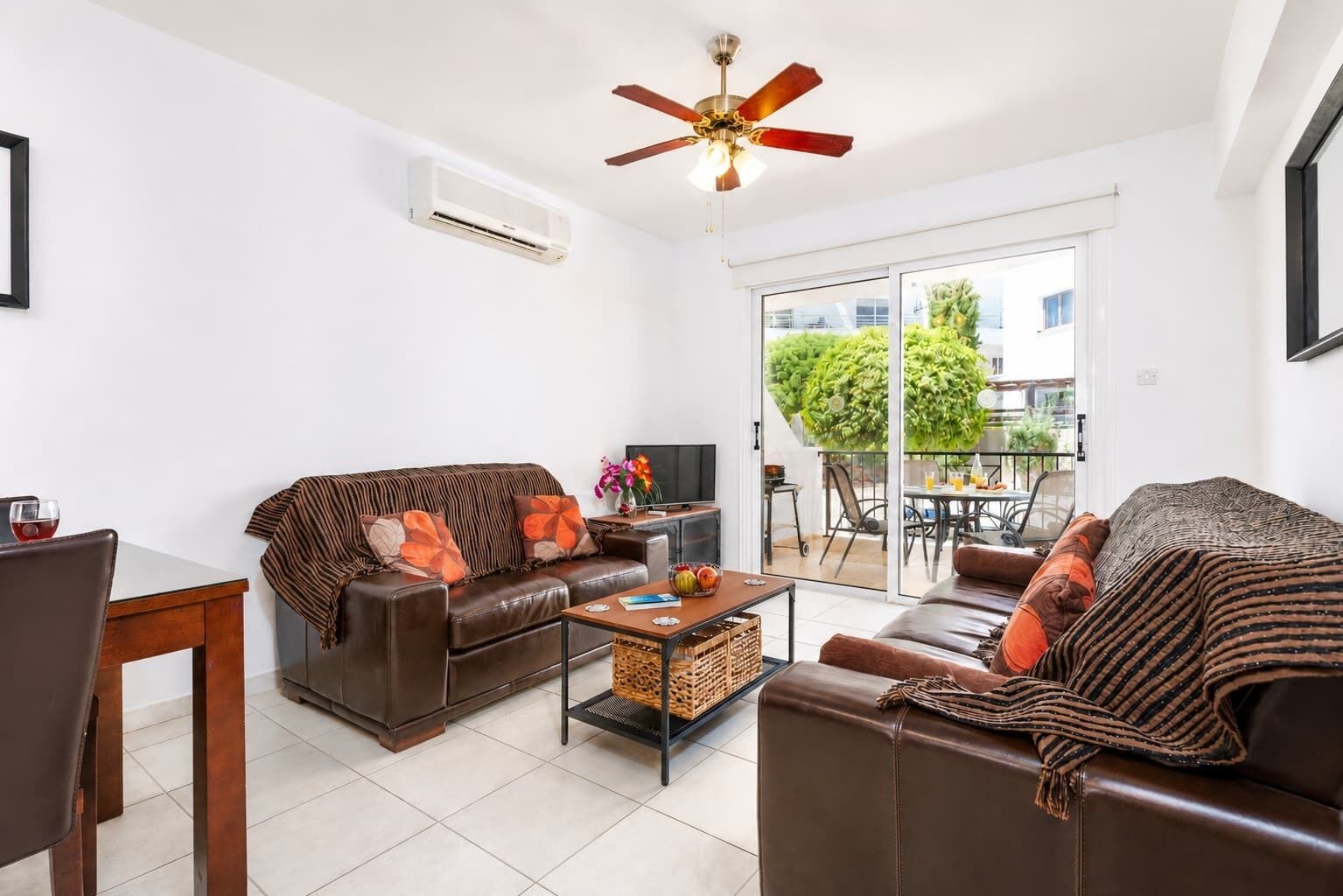 A living room with a sofa, a coffee table, a TV, and a ceiling fan.