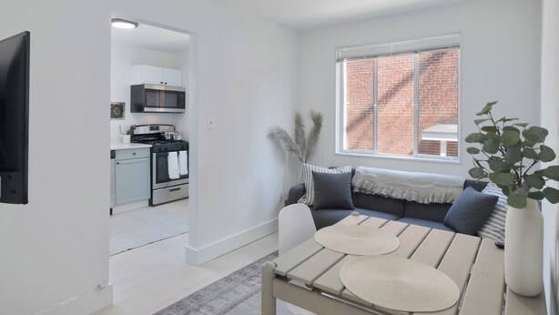 A modern living room with a sofa, a dining table, and a kitchen in the background. - 4206 Washington Blvd Condos (Arlington)