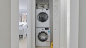 A laundry room with two stacked washing machines and a laundry basket on top. - 4206 Washington Blvd Condos (Arlington)
