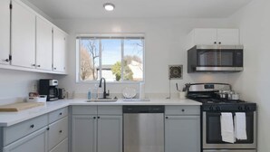 A modern kitchen with white cabinets, a stainless steel dishwasher, a gas stove, and a microwave. - 4206 Washington Blvd Condos (Arlington)