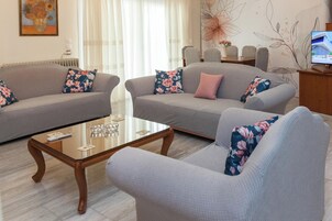 Una sala de estar con dos sofás grises, una mesa de centro de vidrio y cojines estampados.