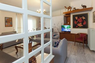 Una sala de estar con un sofá gris, una mesa de centro de madera, un televisor y una silla roja.