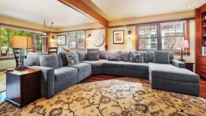 A spacious living room with a large L-shaped sectional sofa, a patterned rug, and a wooden bookshelf. - High Jinks - New Listing! (Cannon Beach)