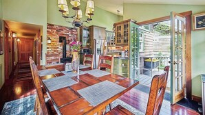 A dining area with a wooden table, chairs, and a brick wall. - High Jinks - New Listing! (Cannon Beach)