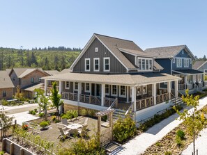 Ein zweistöckiges Haus mit überdachter Veranda und einem umzäunten Garten.