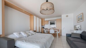 Ein moderner, hell eingerichteter Raum mit Bett, Sofa, Essbereich und Küche.