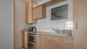 Eine kleine Küche mit Holzausbau, einem Edelstahlbackofen und einem Fenster über der Spüle.