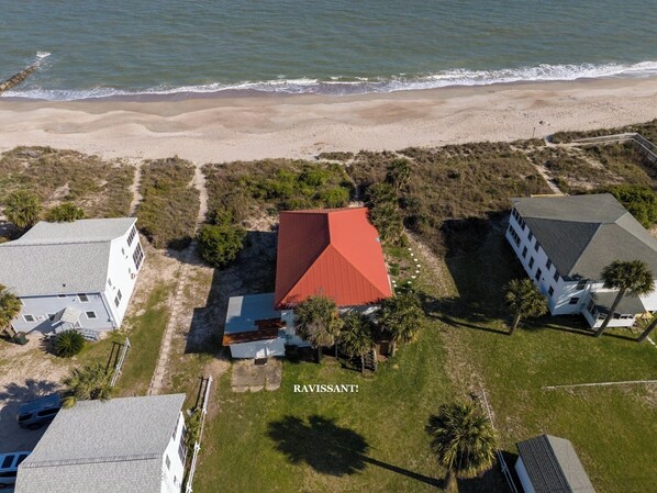 An aerial view of a coastal property with a red-roofed central building, surrounded by white buildings and palm trees, with a beach in the background. - OCEANFRONT, Four Bedroom 2 Bath Beach house ~ The Ravissant! (Edisto Island)