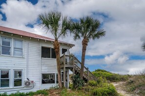 A white two-story house with a balcony and palm trees, surrounded by greenery. - OCEANFRONT, Four Bedroom 2 Bath Beach house ~ The Ravissant! (Edisto Island)