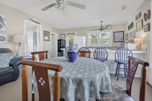 A dining area with a round table, blue chairs, and a ceiling fan. - OCEANFRONT, Four Bedroom 2 Bath Beach house ~ The Ravissant! (Edisto Island)