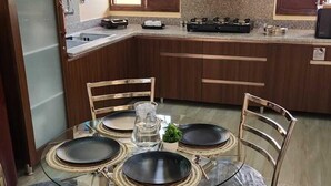 Une cuisine moderne avec une table de salle à manger ronde, six chaises, une cuisinière à gaz et un four encastré.