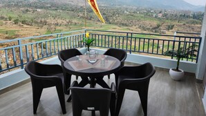 Un balcon avec une table et des chaises, un drapeau et une vue sur un paysage montagneux.