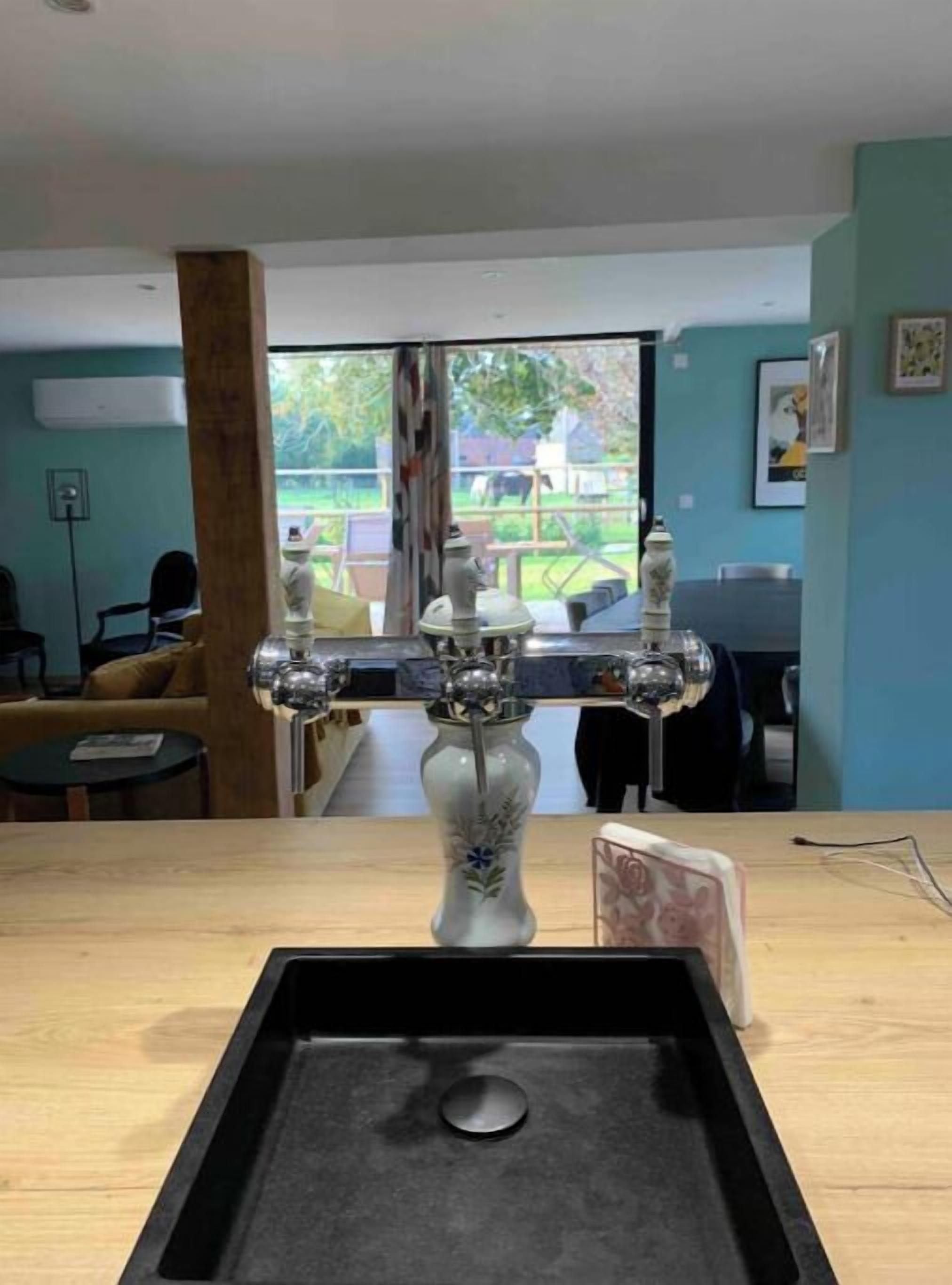 Een kamer met een groot raam, een houten tafel en een vaas met een bloemistisch ontwerp.