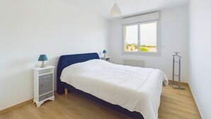 A bedroom with a bed, nightstands, a window, and a radiator. - Flat for 4 in the town centre - near by tren station (Saint-Hilaire-de-Riez)