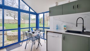 A modern kitchen with a large window, a dining table with chairs, and a dishwasher. - Quiet house for 6 - Less than 2km from the beach (Dinard)