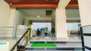 A hotel entrance with a glass facade, a staircase, and a green mat at the bottom. - Hotel Giriraj Palace (Jaipur)