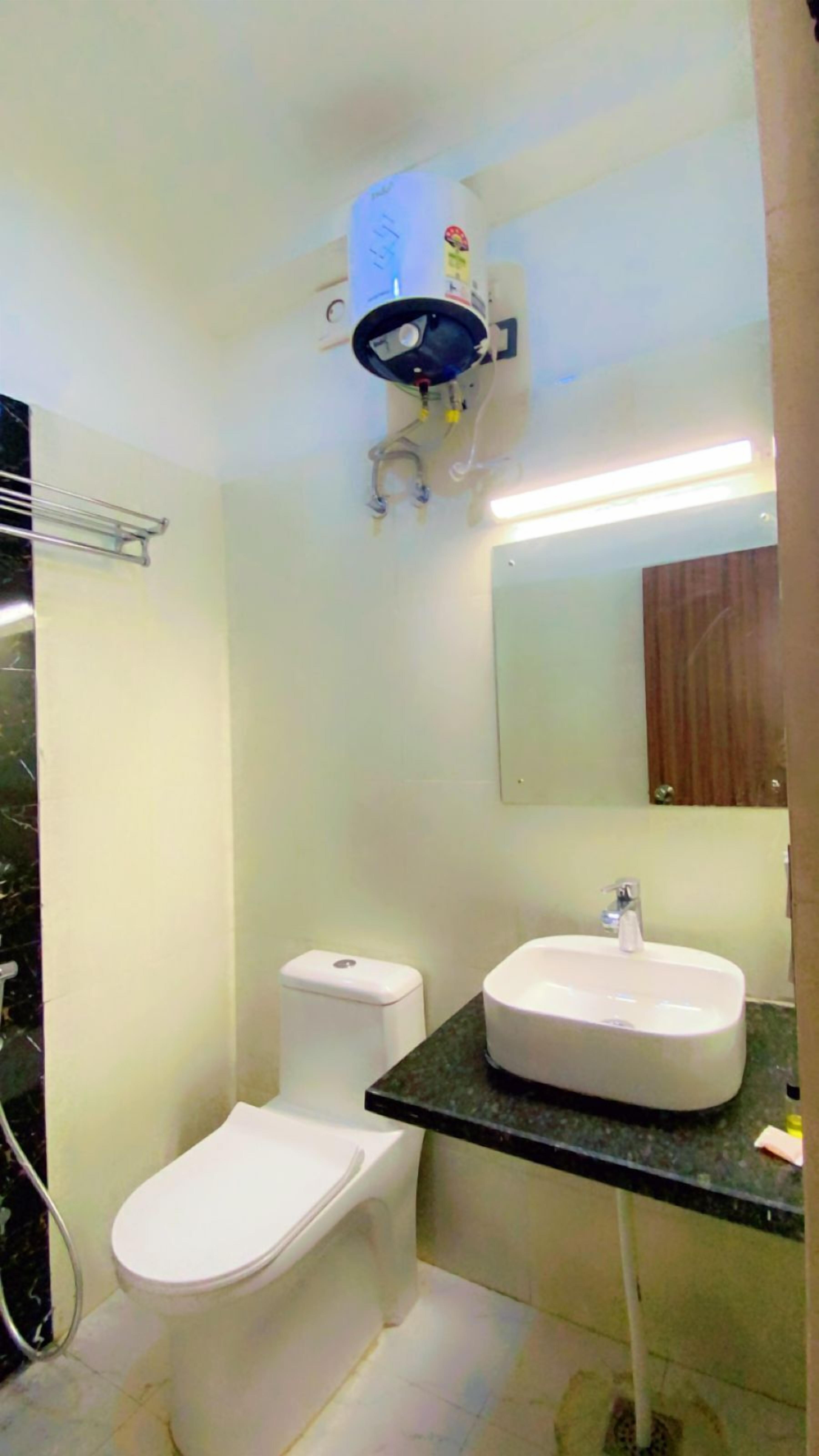 Un baño con inodoro, lavamanos y purificador de aire instalado en el techo.