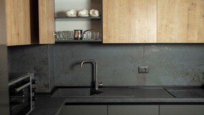 A modern kitchen with dark cabinetry, a stainless steel sink, and a built-in oven.