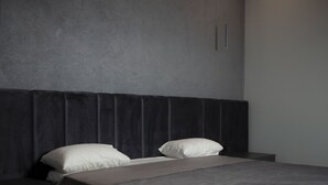 A modern bedroom with a large bed, two pillows, a bedside table, and a nightstand.