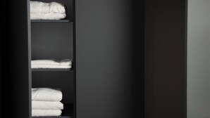 A dark interior with a shelving unit holding neatly folded white towels.
