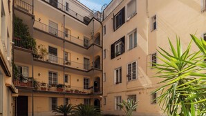 Un edificio de varios pisos con balcones, plantas en macetas y un patio.