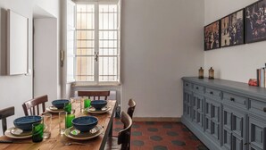 Un comedor con una mesa de madera dispuesta para cuatro, un armario azul y un ventanal grande.