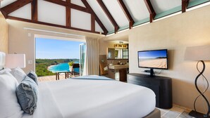Ein Hotelzimmer mit einem großen Bett, einem Fernseher, einem Schreibtisch und Blick auf den Ozean.