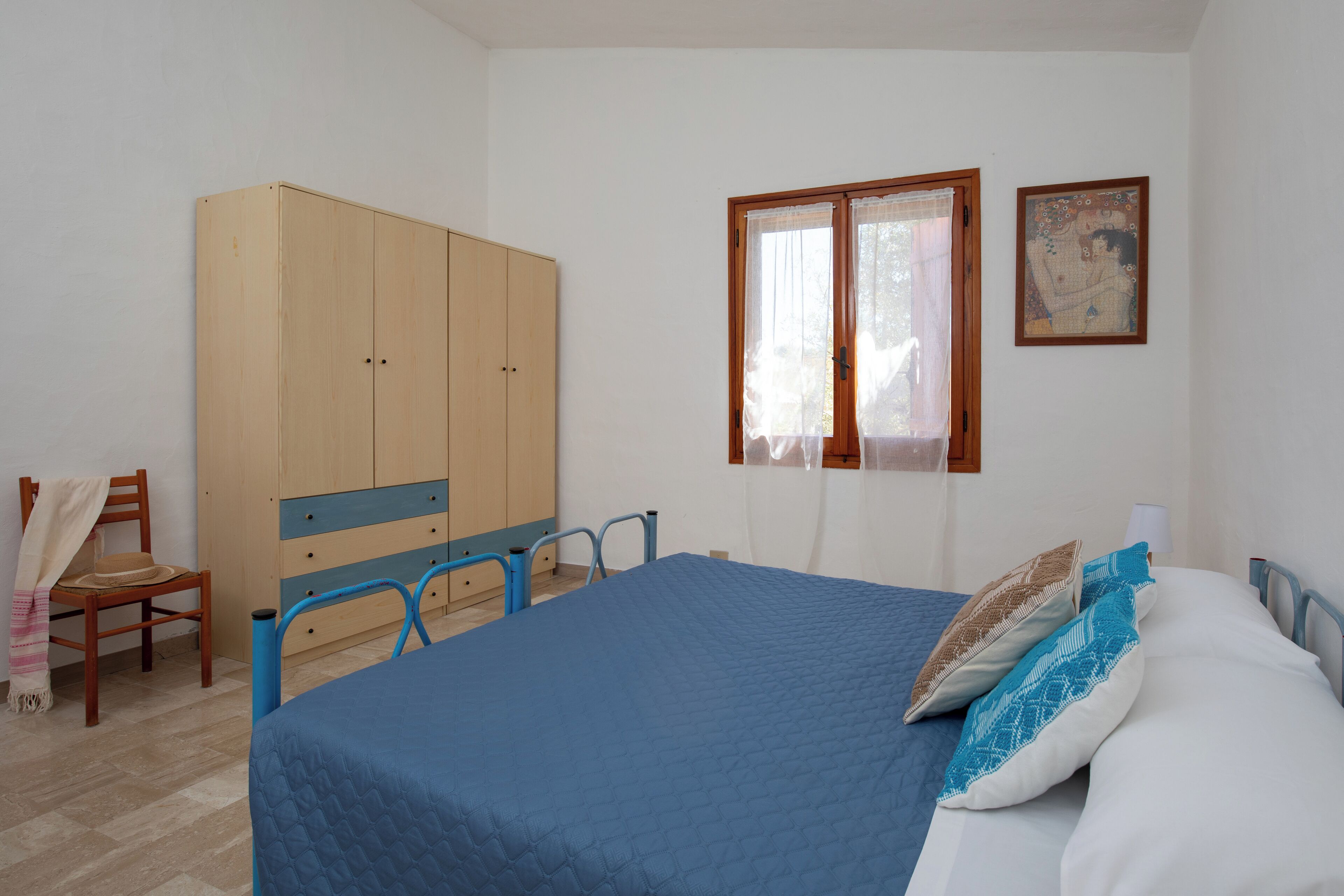 Une chambre à coucher avec un lit, une armoire, une chaise et une fenêtre avec des rideaux.