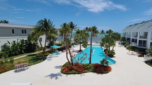 Ein Resort mit Pool, umgeben von Palmen und einem weißen Gebäude mit Balkonen.