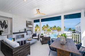 A spacious outdoor patio with a grill, wicker furniture, and a view of the ocean. - Modern Keys Penthouse W Private Beach Pool (Islamorada)